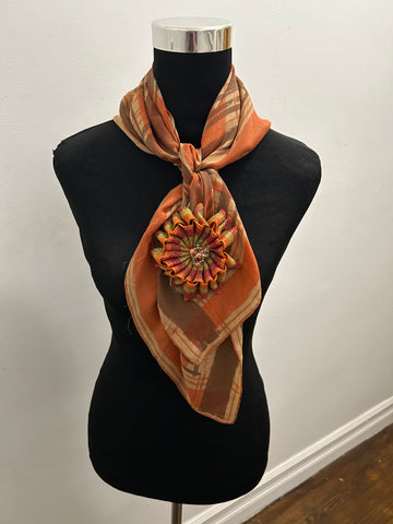 Multi-colored vintage scarf in brown, orange, and gold with matching flower brooch in plaid ribbon.